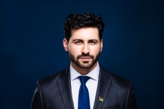 man in suite serious face for headshot photo with black back drop