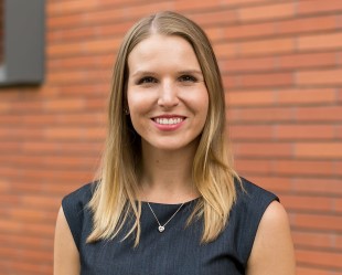 woman smiling with dress on in front of brick building